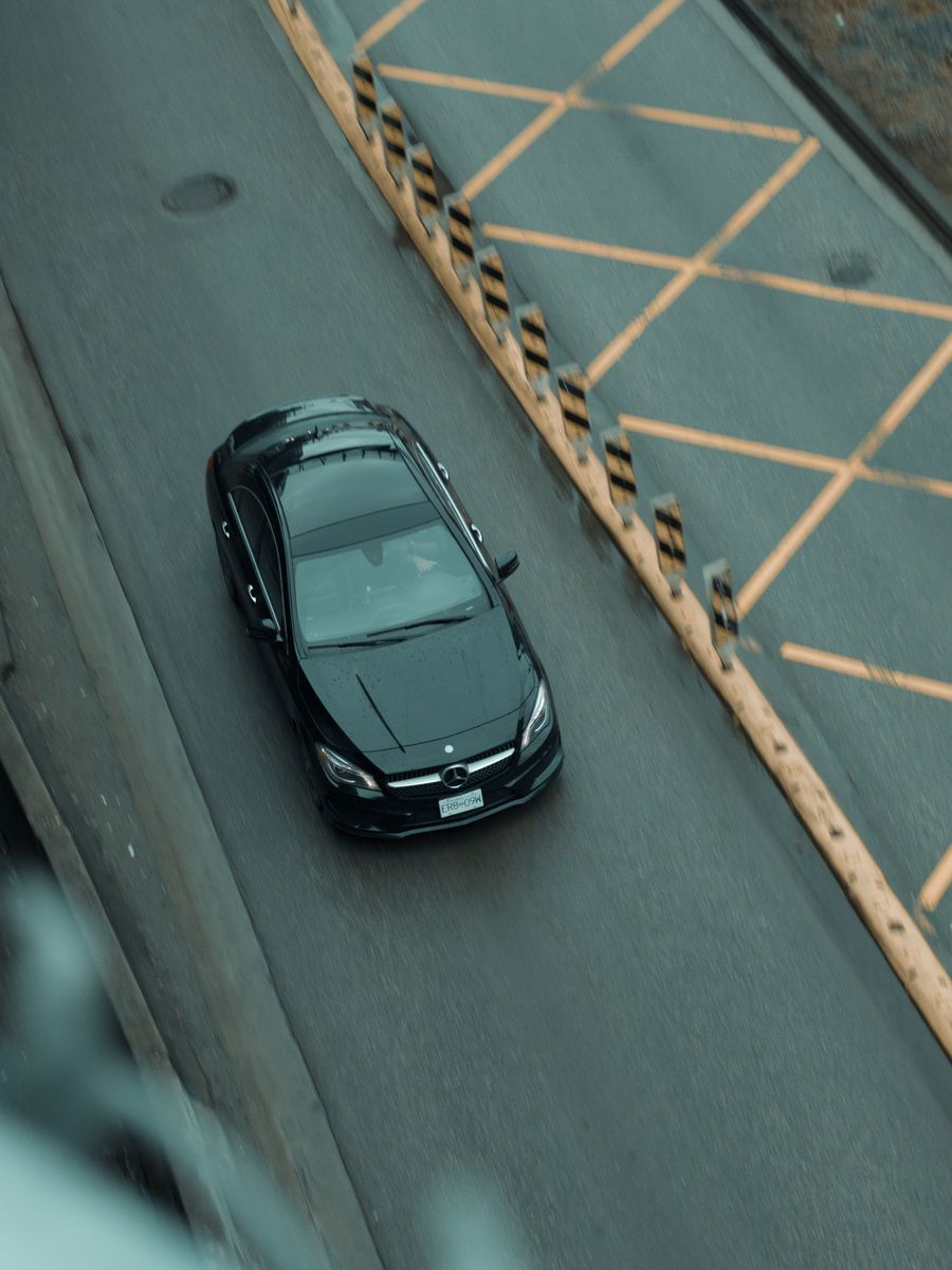 Black Mercedes seen from above, driving along a city road